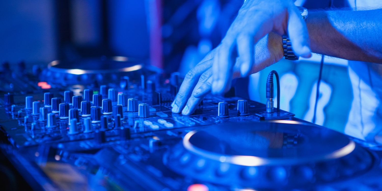 DJ playing music at mixer on colorful blurred background