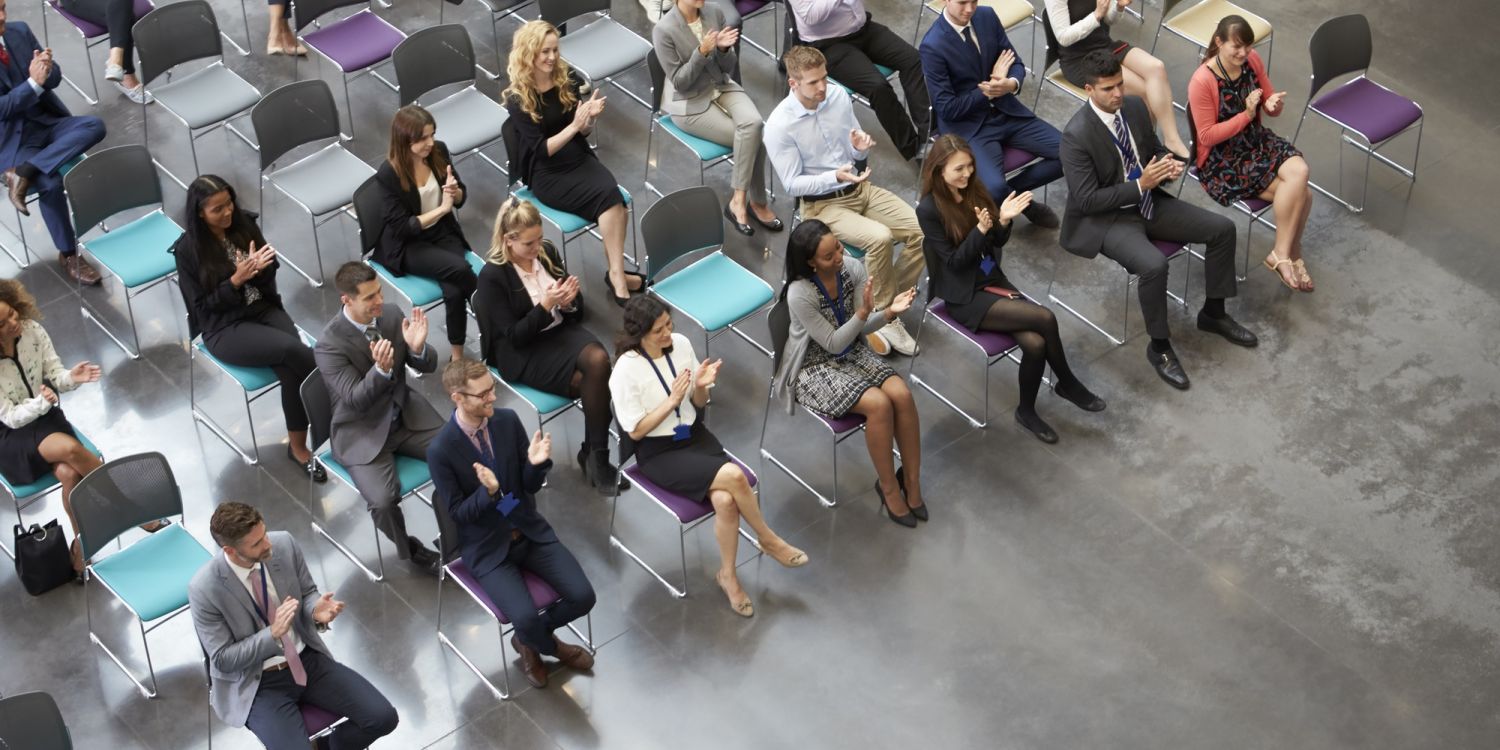 Overhead View Of Audience Applauding Speaker At Conference